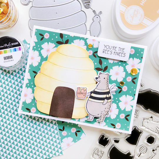 "You’re the bee’s knees" card featuring a bear with a honey pot beside a beehive, accented with floral paper.