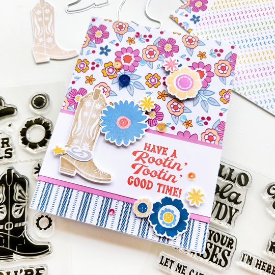 A card with "Have a rootin' tootin' good time" sentiment, featuring floral cowgirl boots on striped and floral-patterned paper, adorned with large, colorful flowers.