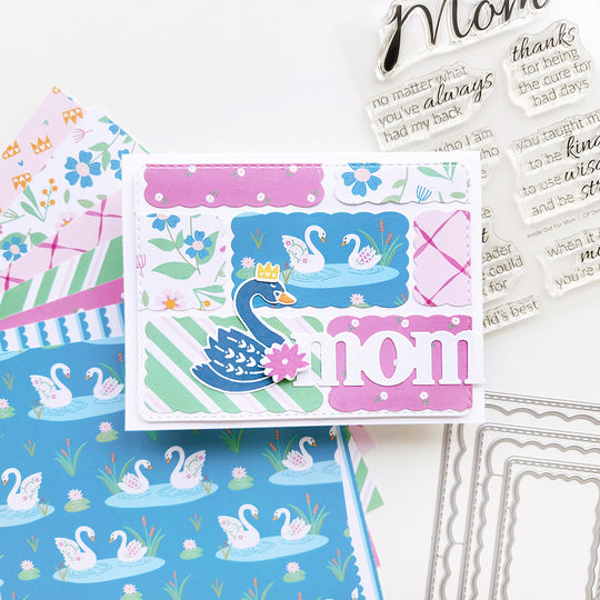 Mom card with a blue swan, set among various patterned papers featuring graceful swans, delicate florals, and soft ribbon accents.