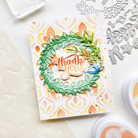 Handmade card with 'thank you' message and decorative elements on a white surface with crafting tools.