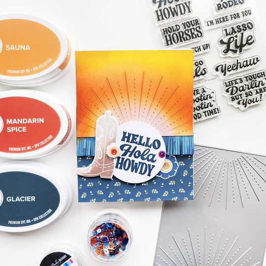 A card with ink blending sunray, fringe, floral patterned paper, and an accent cowgirl boot with the sentiment "Hello Hola, Howdy.