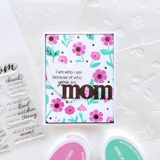 "Mom, I am who I am because of you" card set against a soft background of pink and green florals.