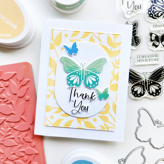 Thank you card with butterfly design surrounded by stamping tools on a white background