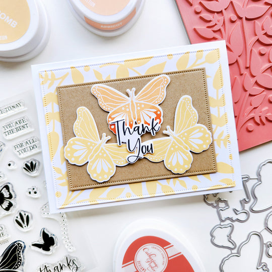 Card with butterfly design and 'Thank You' text, surrounded by crafting tools on a white background