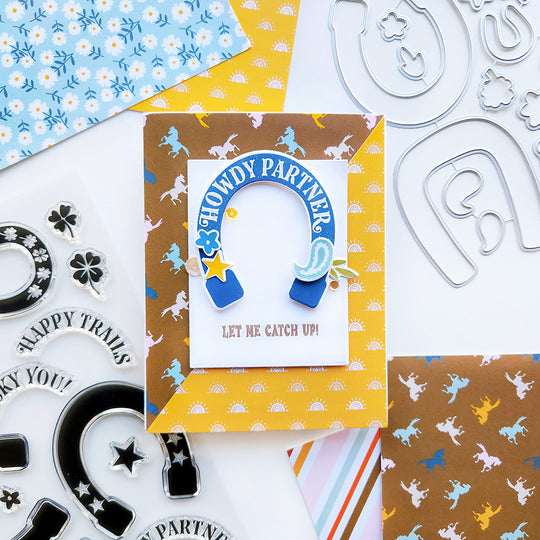 A card with a horseshoe, horse, and rainbow sunshine paper, featuring the playful sentiment "Howdy Partner Let Me Catch Up" for a fun, western touch.