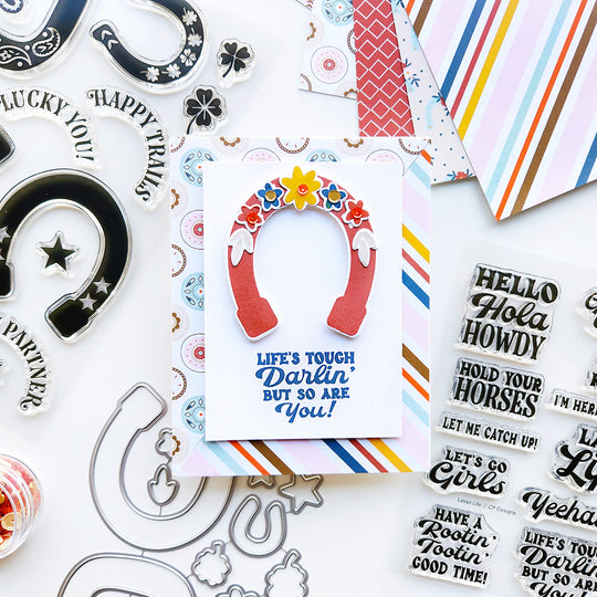 A charming card with a floral horseshoe and Howdy Partner patterned paper, featuring the empowering sentiment, "Life’s tough Darlin, but so are you."