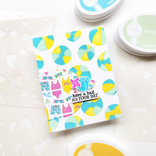 "Have a ball it's your day" card with swimsuit-themed paper set on a beach ball background.