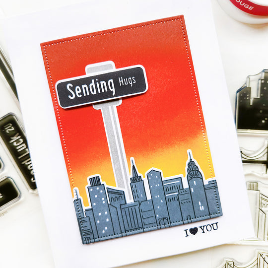 Sending Hugs Street Sign with a city scape ombre sunrise card