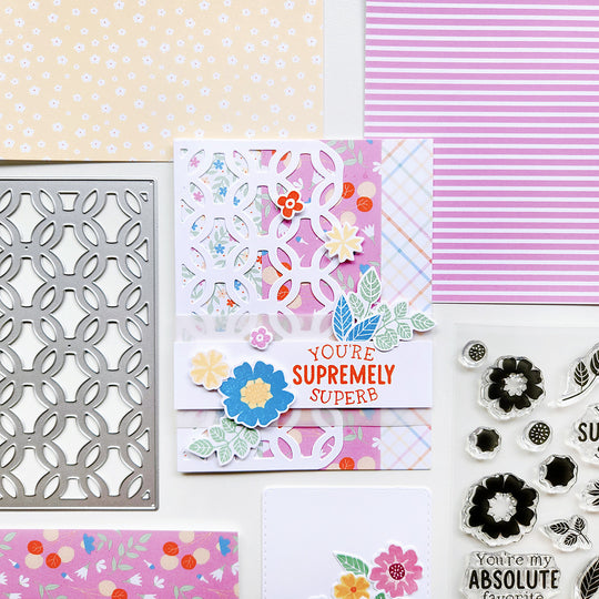 Crafting materials including a card with floral design, stencils, and stamps on a patterned background.