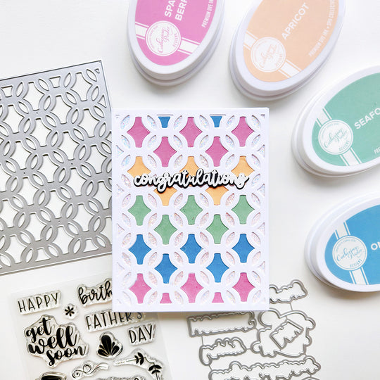 Card with geometric pattern and 'congratulations' text, surrounded by stamping tools on a white background