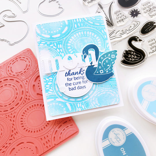 "Mom, thanks for being the cure for bad days" sentiment card featuring a blue swan on a rippled lake effect background.