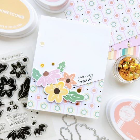 "Miss you, Friend" card featuring a cluster of flowers resting on honeycomb-patterned paper with sequin.