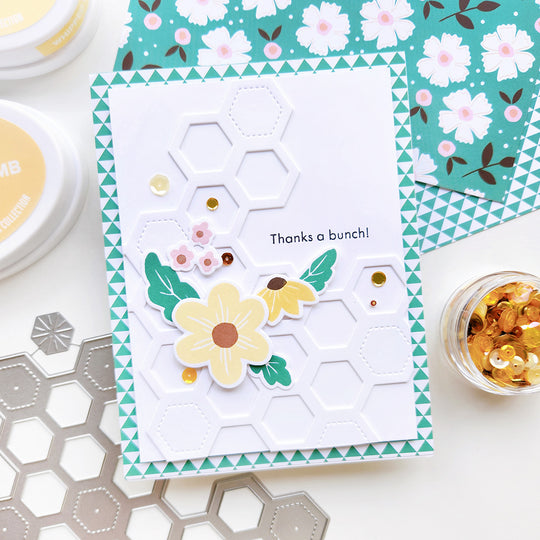 “Thanks a bunch” card with flowers and sequin atop honeycomb shapes and triangle paper.