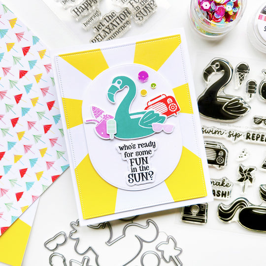 "Fun in the Sun" card featuring a flamingo pool float with a radio, drink, and sunglasses, set on sunray-themed paper.