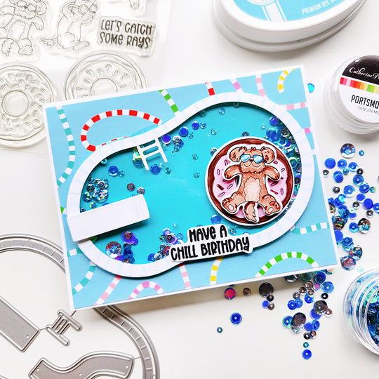 "Have a Chill Birthday" card with a dog on a donut float in a sequin pool, set on pool noodle–themed paper.