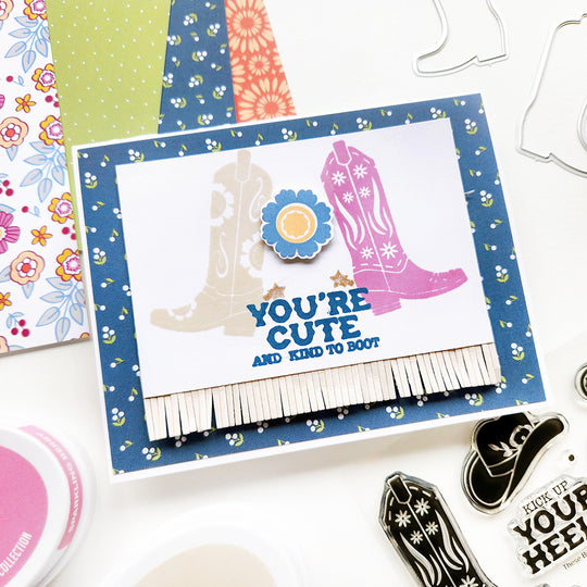 A card with "You're cute and kind to boot" sentiment, featuring butterfly and floral cowgirl boots with fringe, set against a floral-patterned paper background.