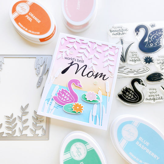 "World's Best Mom" card featuring a swan on a rippled lake with cattails, a lily pad, and hanging vines, set on an ink-blended background.