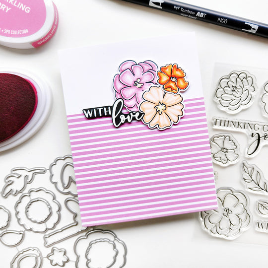 Pink striped notepad with floral stickers on a white background with stamping supplies.
