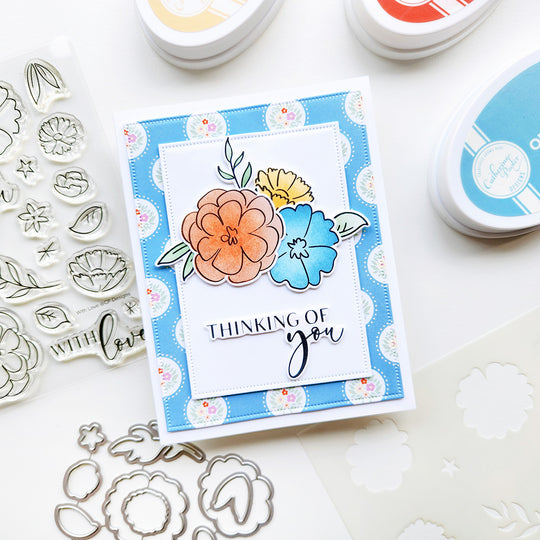 Card with floral design and 'Thinking of you' text, surrounded by stamping tools.