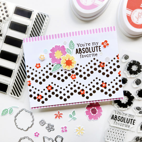 Card with 'You're my absolute favorite' text and floral designs, surrounded by stamping tools on a white background.