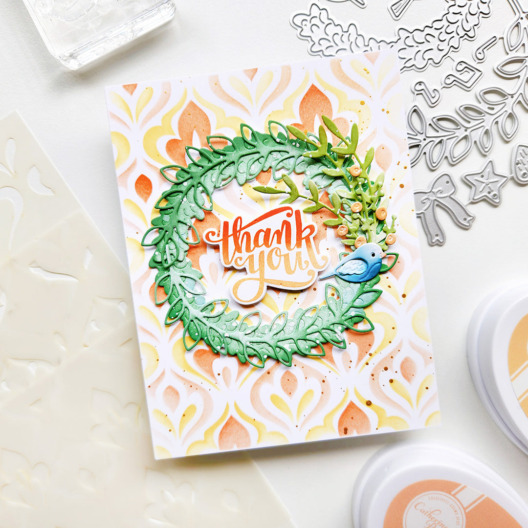 Handmade card with 'thank you' message and decorative elements on a white surface with crafting tools.