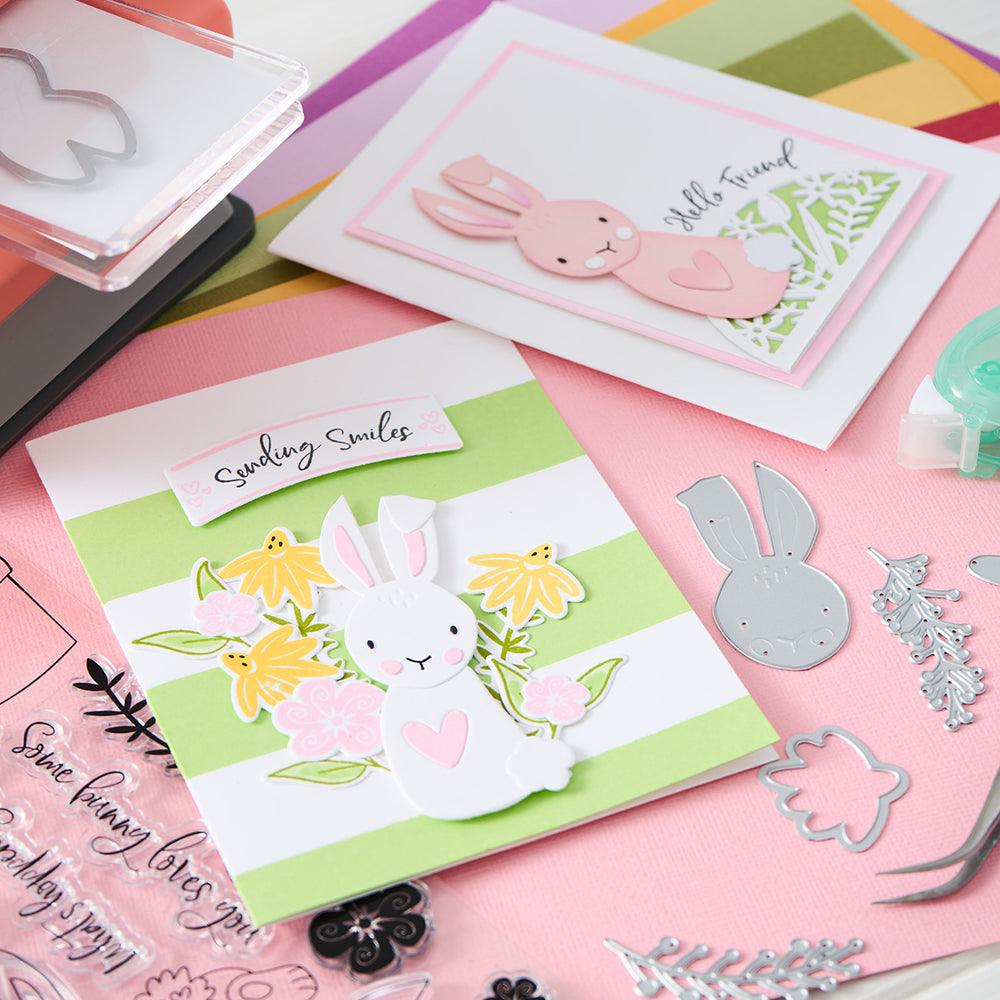 Send smiles with a spring card featuring bunnies, planters, flowers, and a green and white striped background.