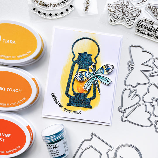 Excited card using Camping Lantern die, Night in Flight stamps and dies, Tiara, Tiki Torch, Orange Twist and Midnight ink pads, with Tarnished Teal embossing powder.
