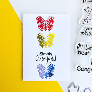 Three colored origami butterflies in a row with simply overjoyed card